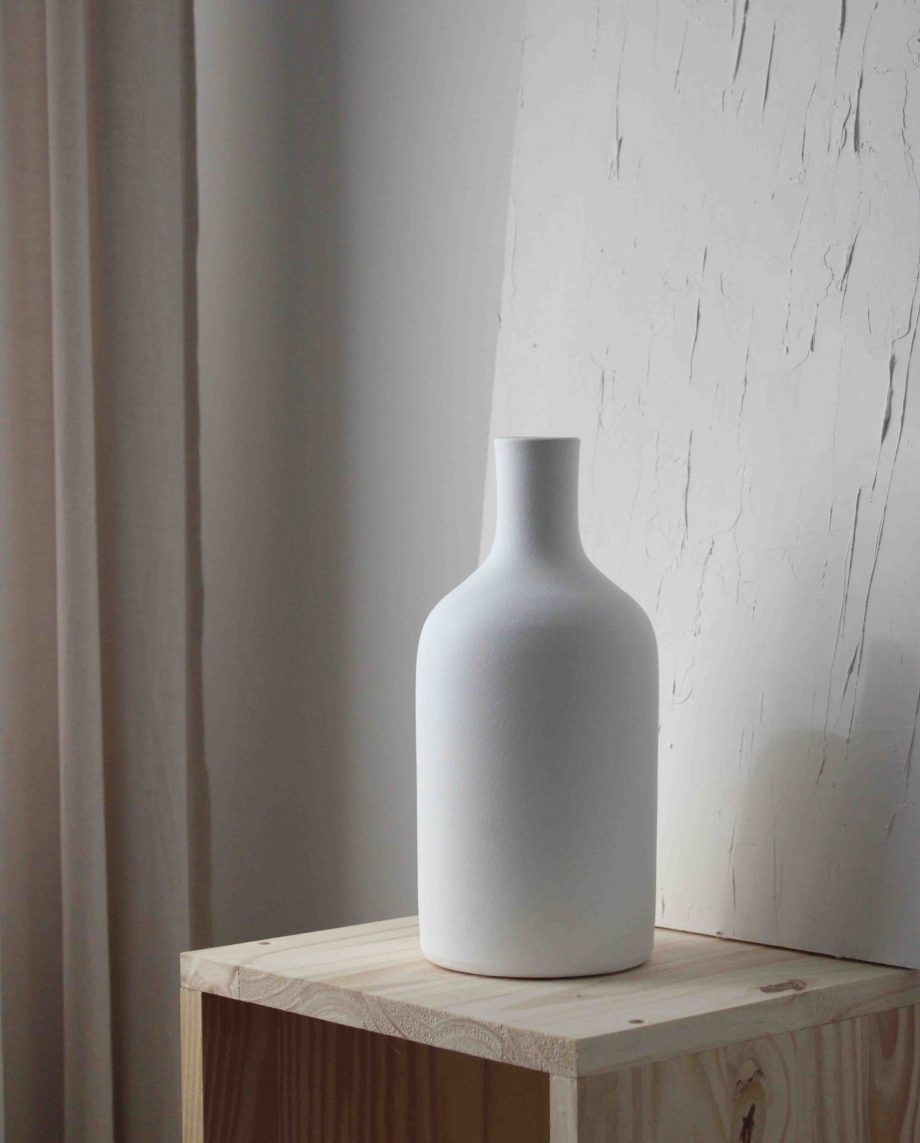 Weiße dekorative Vase in Form einer Flasche.