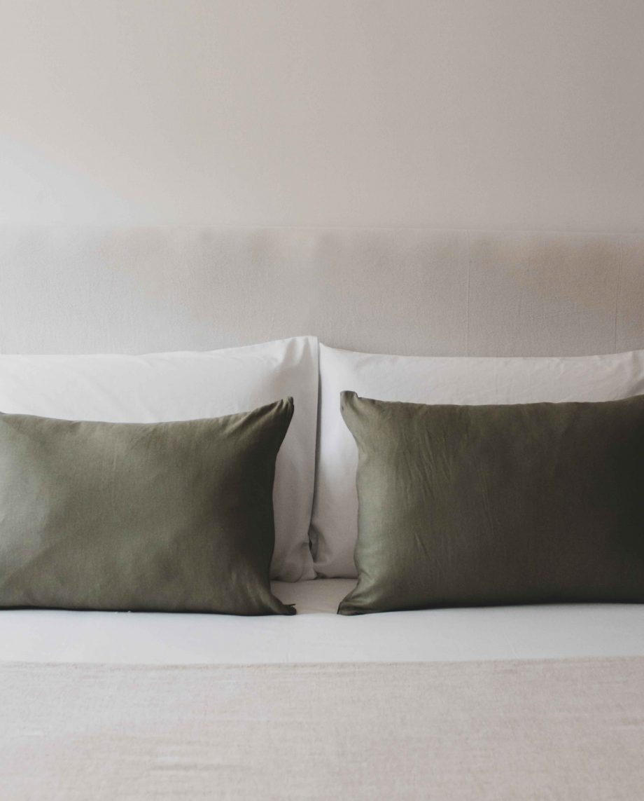 Almofadas com capas de almofada verde oliva na decoração de uma cama.