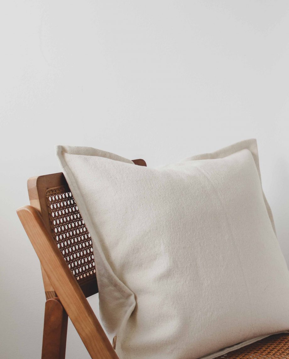 Coussin avec housse texturée sur une chaise en bois.